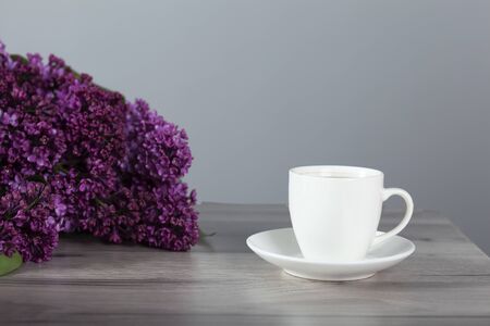 cup of coffee and lilac flowers on tableの写真素材