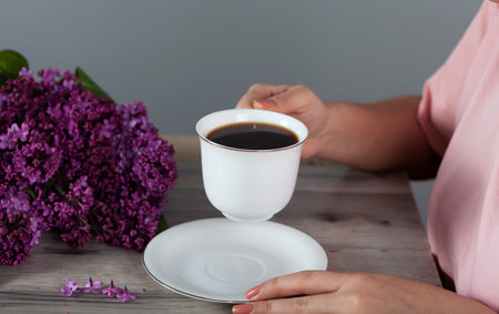 woman drink coffee and lilac on the tableの写真素材