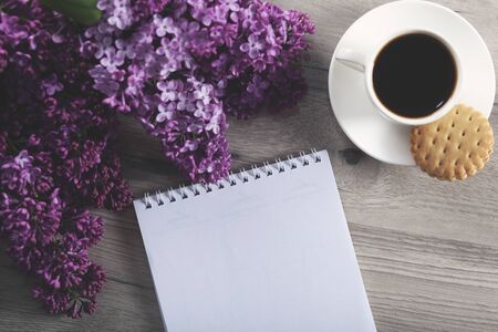 notepad and coffee with lilac on the tableの写真素材