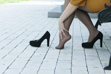 woman hand in ache  feet and high-heeled shoesの写真素材