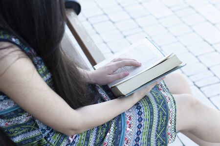 young woman reading book in the streetの写真素材