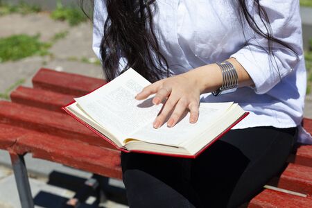 young woman reading book in the streetの写真素材
