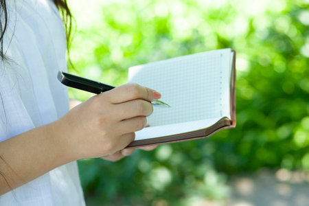 woman hand  pen with notepad  in the park background