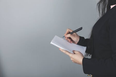 woman hand holding pen and notepad on gray backgroundの写真素材