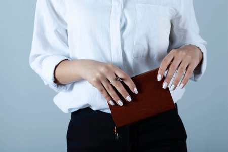 Beautiful business woman portrait hold pen and notebook on gray