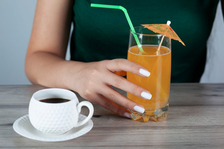 woman hand with Orange juice in coffee on the desk