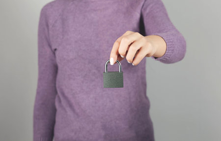 woman holding lock on gray backgroundの写真素材