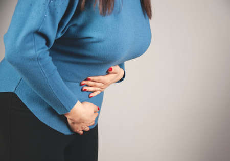 woman hand in ache stomache on gray backgroundの写真素材