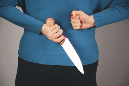 woman hand holding a knife in back on gray backgroundの写真素材