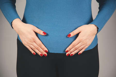 woman hand in ache ovaries on gray backgroundの写真素材