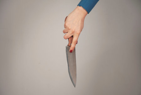 woman hand holding knife in back on gray background