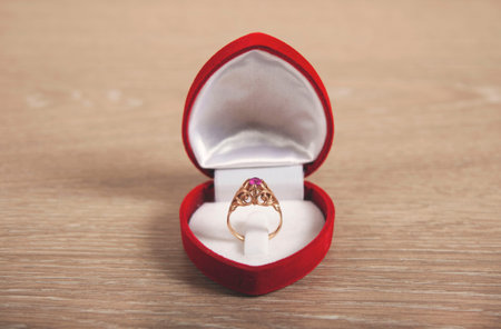 holding red box with ring on gray background
