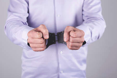 man hand handcuffs in back on the dark backgroundの写真素材