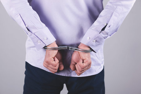 man hand handcuffs in back on the dark background