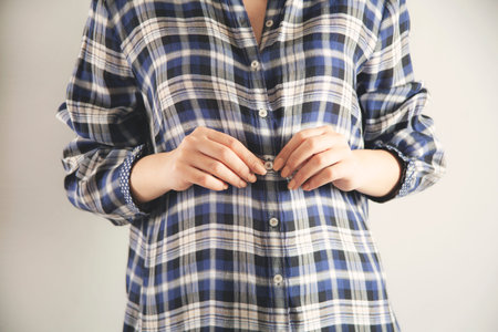business woman hand shirt button on gray background