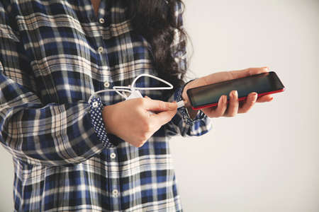woman hand holding phone charger on gray backgroundの写真素材