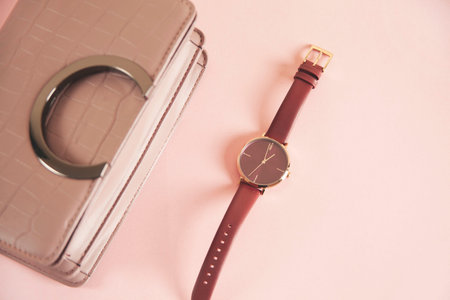 woman bag with watch on the pink table