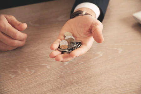 businessman hand holding coins putting in jar concept finance and accounting savingの写真素材