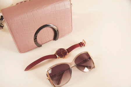 woman bag with sunglasses on the pink table