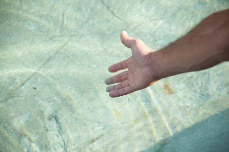 young man hand in the pool waterの写真素材