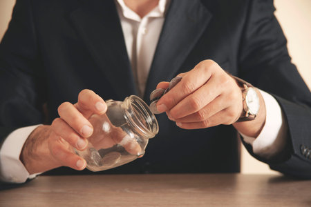 businessman hand holding coins putting in jar concept finance and accounting savingの写真素材