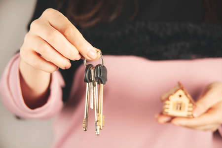 woman hand holding wooden house model on gray backgroundの写真素材
