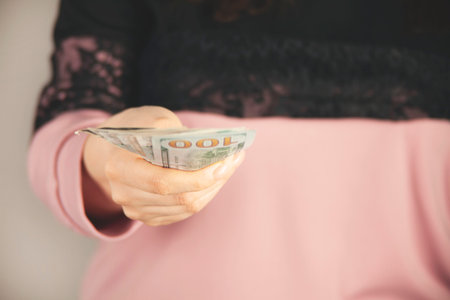 young woman hand money on gray background