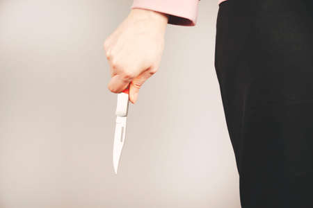 woman hand holding knife in back on gray backgroundの写真素材