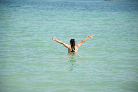 young girl in swimsuit is playing in the water in the sea.