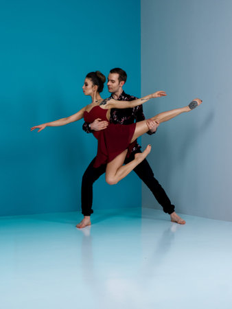 Modern ballet dancer couple in black trousers black in roses shirt and bordo dress performing art...