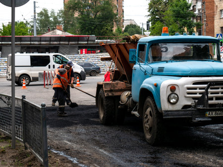 Workers making asphalt with shovels at road construction.のeditorial素材