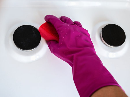 Cleaning Service Concept. Hand in rubber glove cleaning gas kitchen stove.