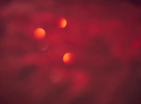 Blurred background lights. Abstract defocused gold, white, red and yellow glitters texture on black background. Shining glowing snow effects.の写真素材
