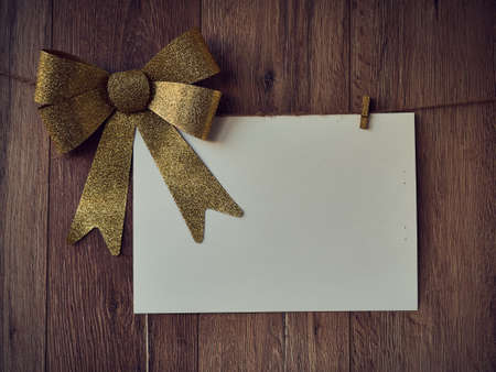 Bow Decorations with text space on white paper on a wooden background. Vintage greeting card. Holiday decorations and free space for text on a wooden background. Holidays decor on the clothespins. Vintage texture. Copy space.の写真素材