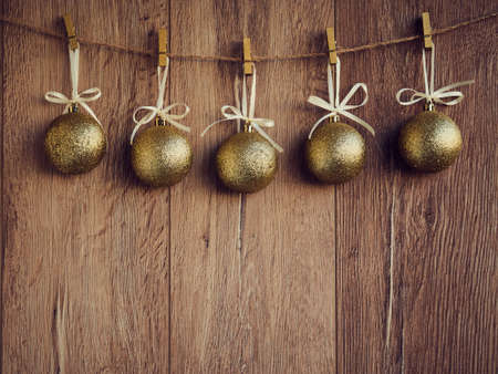 Christmas decorations golden snowballs on the wooden background. Christmas decorations, toys for the Christmas tree hanging on clothespins. Copy Space.の写真素材