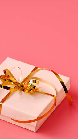 Holiday background. Gift box with gold ribbon and lights on a pink background. Holiday background. Valentines day.の写真素材