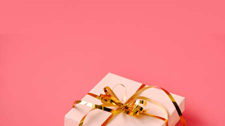 Holiday background. Gift box with gold ribbon and lights on a pink background. Holiday background. Valentines day.の写真素材