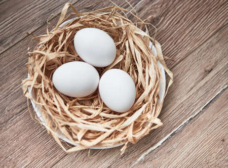 Easter composition on wooden background, Easter background with Easter eggs in nest and spring flowers. Top view with copy space.の写真素材
