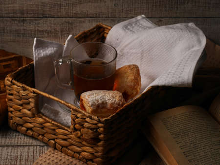 Tea and sweet cookies in a wicker tray on white wooden background. Open Book near the afteroon tea.の写真素材