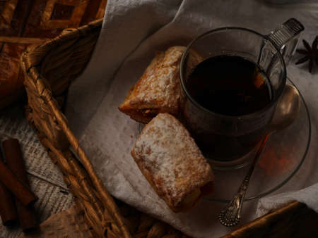 Tea with sweet cookies in a wicker tray on white wooden background. Cinnamon stiks lay near the afteroon tea.の写真素材