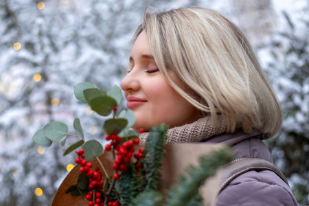 A lonely young woman enjoys a Christmas bouquet in a snowy winter park. Self-love, loneliness in the buzz.の写真素材