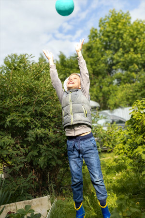 boy on dacha site playing ball on summer dayの写真素材