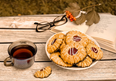 Tea with qurabiya sand cookies while reading book in fall garden. Autumn dessertの写真素材