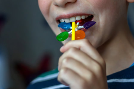 7 year old boy enjoys lollipop. Harmful food. Sugar addiction. Damage to tooth enamel. Close-up.の写真素材