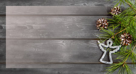 Wooden Christmas background with natural pine needles, cones and silver angel. Frame, banner, postcard.の写真素材