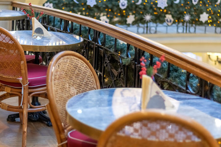 An empty cafe with Christmas decor, tables and wicker chairs close-up.