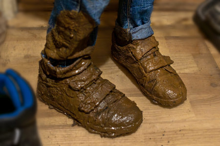 Close-up of feet in boy's muddy boots, standing guiltily in the hallway.