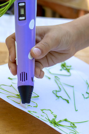 Childs hand creates figures with a 3D pen. Close-up