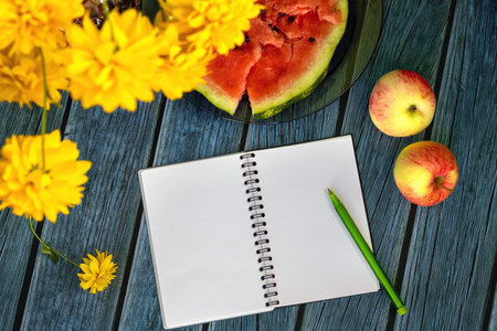 Still life with apples, watermelon, fall flowers and an open notebook with pen for notes. Late...
