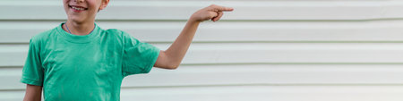 Mockup with an unrecognizable child showing direction. Copy space, blank wall. Boy is smilingの写真素材